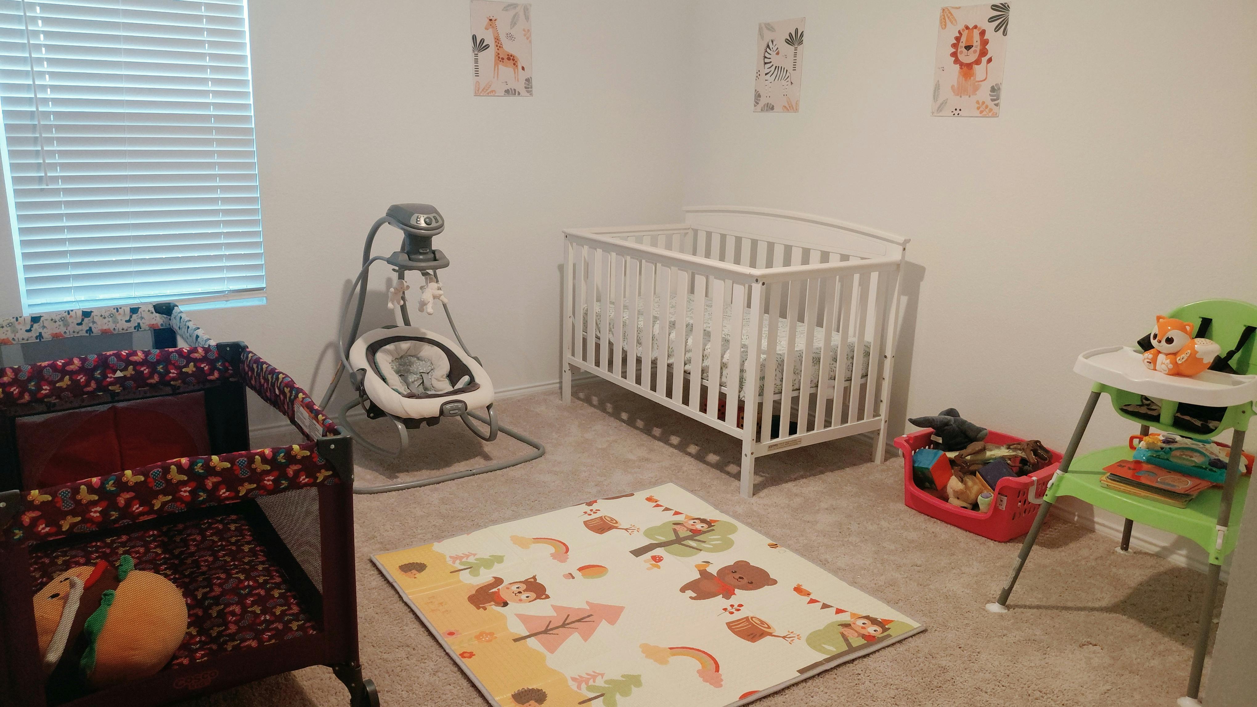 Crib, baby swing, playpen, and feeding chair in a nursery