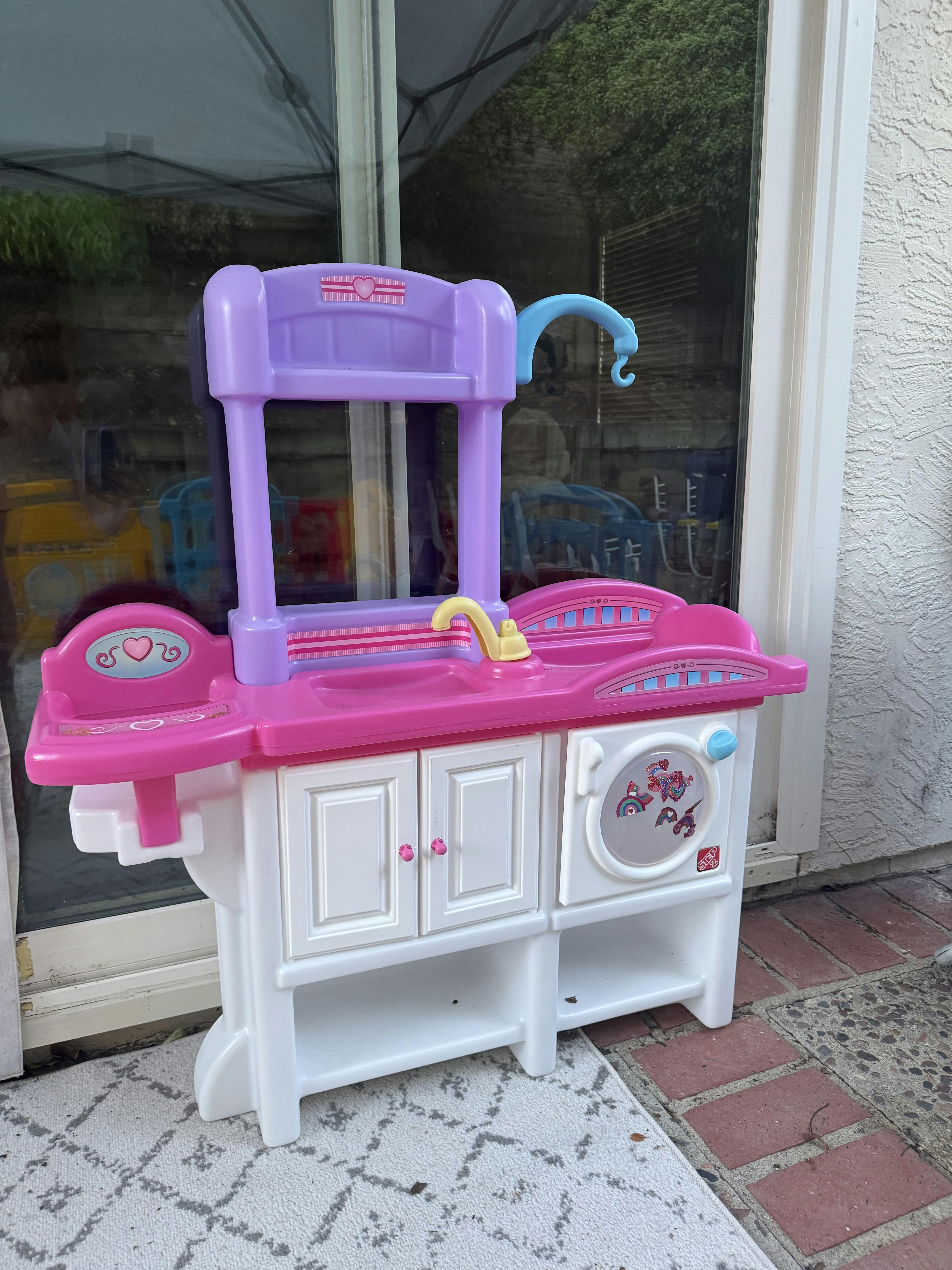 Child's toy kitchen set with a sink, faucet, and pretend appliances