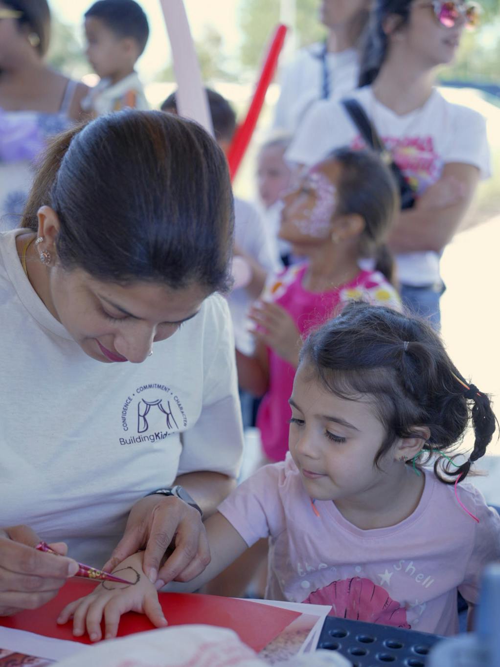Person drawing henna design on a child's hand