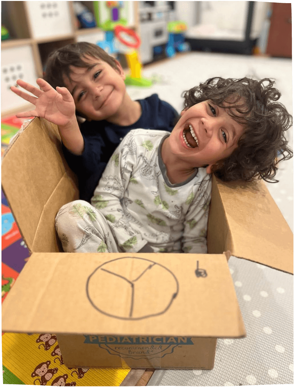 Two children playing in a cardboard box