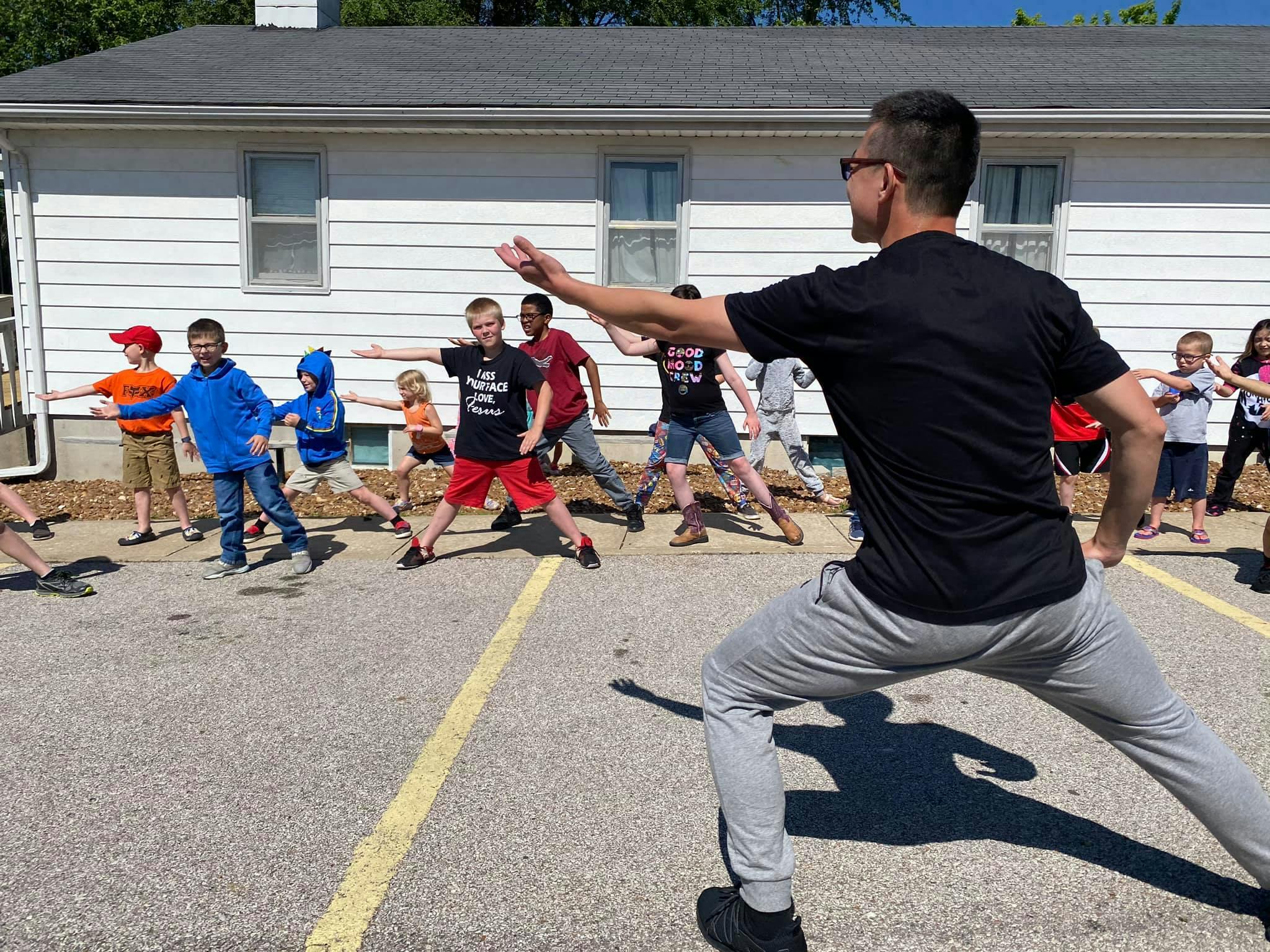 Adult and children doing a martial arts pose outdoors