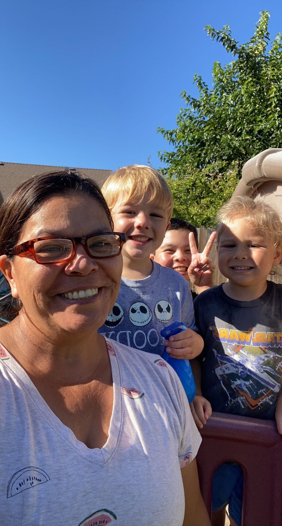 Person in glasses smiling with three children behind them