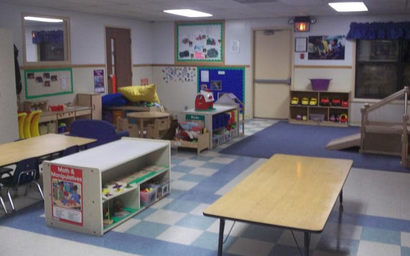 Classroom with child-sized furniture and play areas, checkerboard and blue carpet