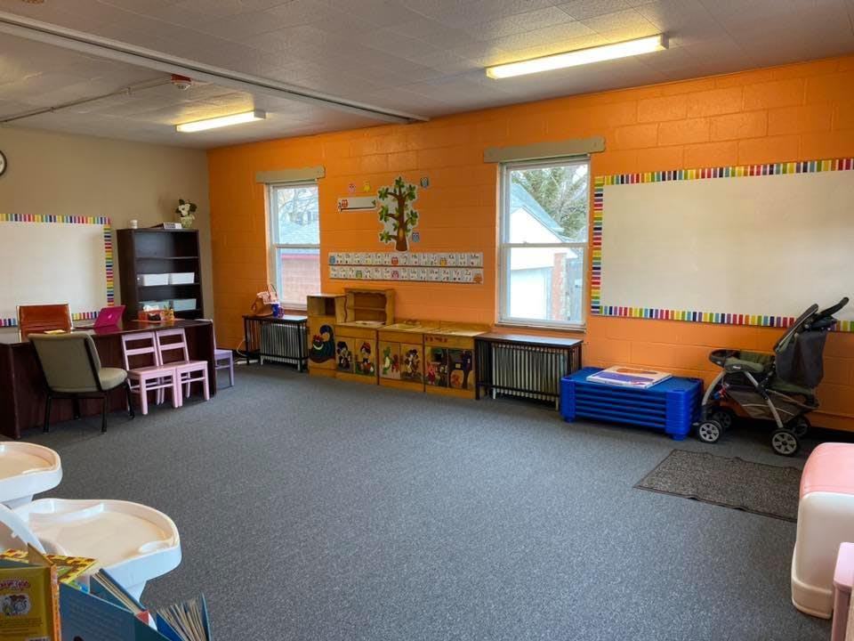 Classroom with orange walls, whiteboard, and small furniture