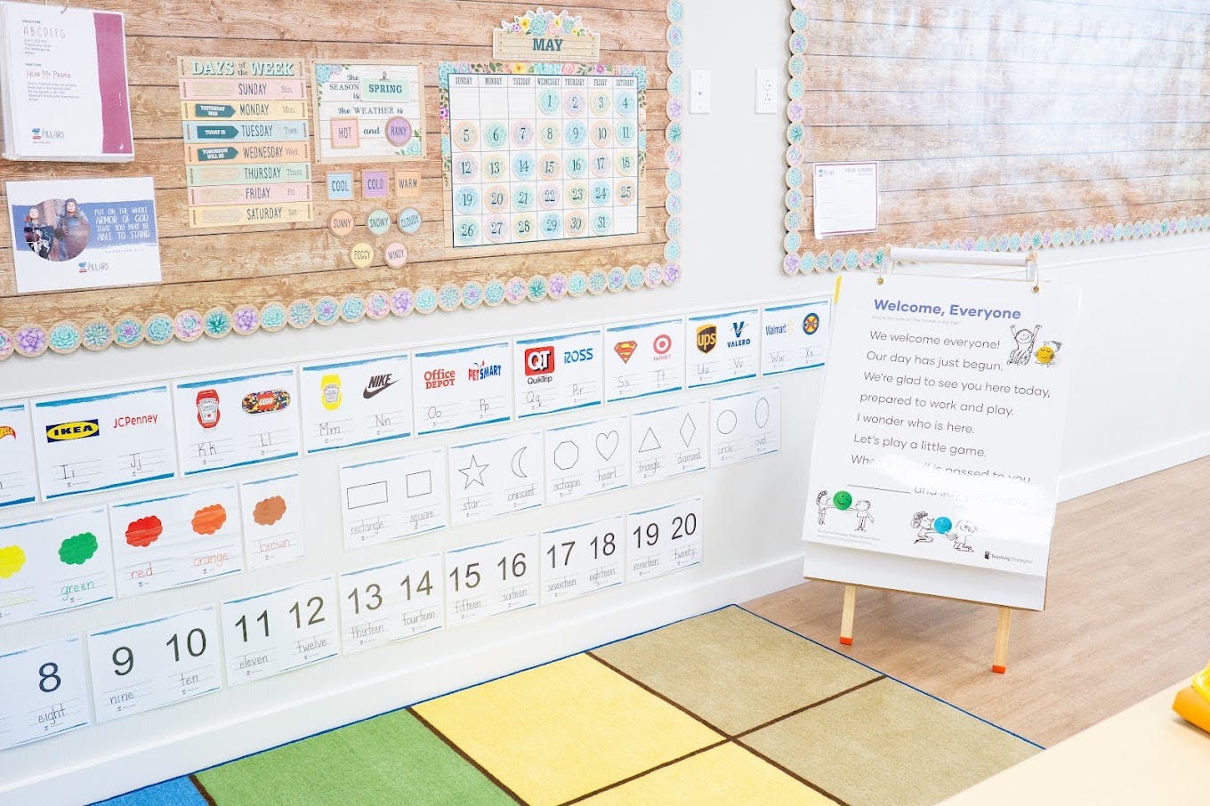 Classroom wall decorated with educational posters, charts, and a welcome sign