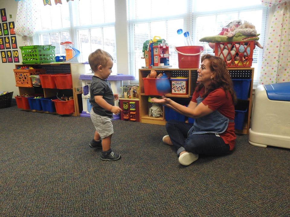 Adult sitting on floor playing with child in a classroom