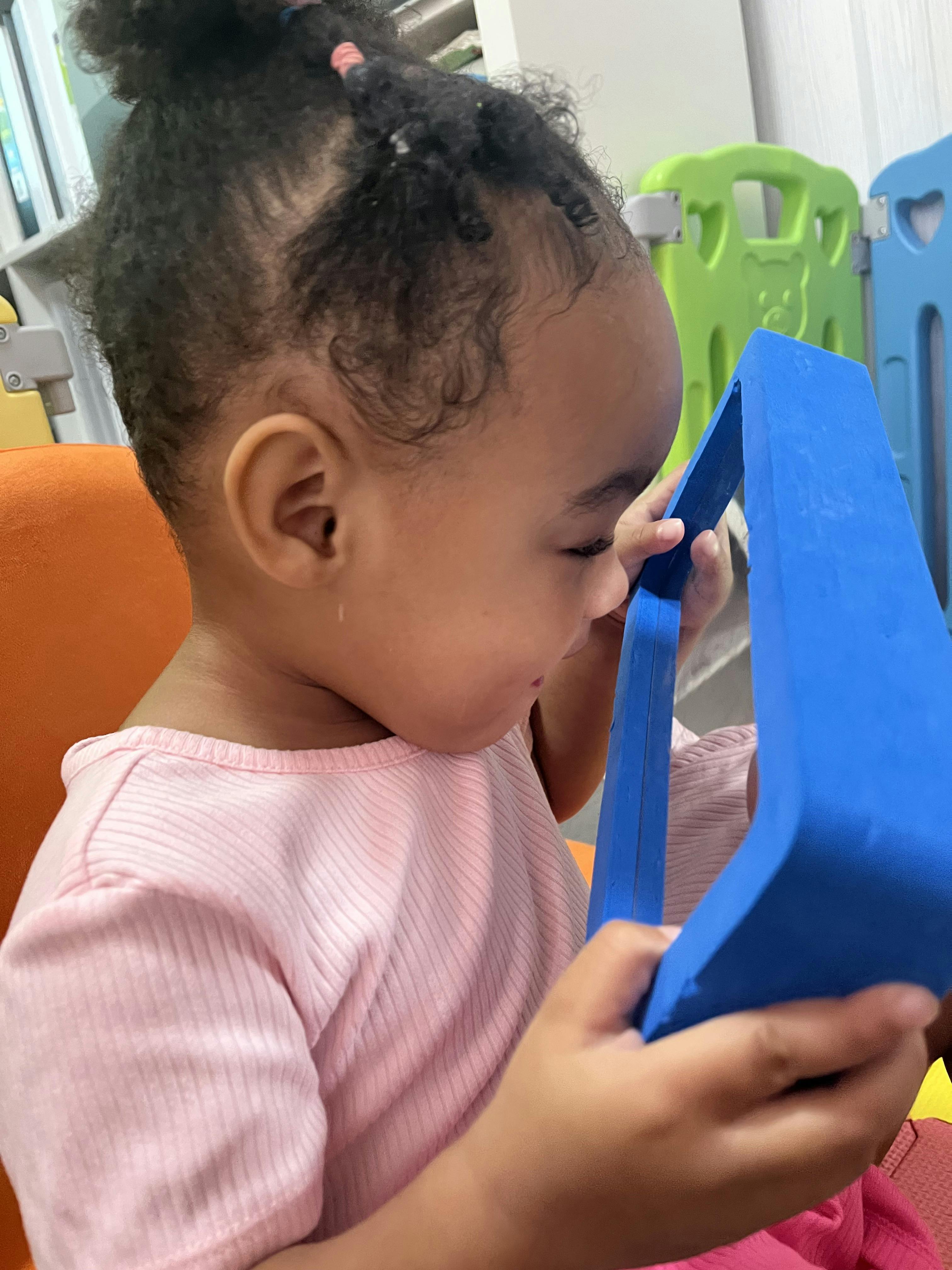 Child playing with a blue geometric shape