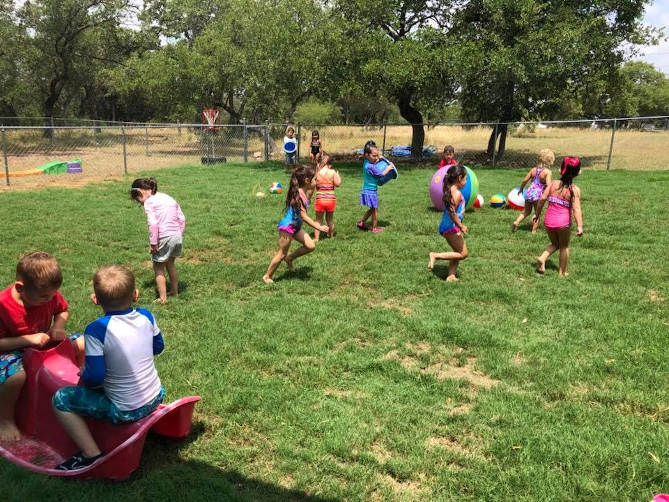 Children playing in swimsuits on a grassy lawn