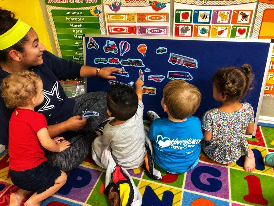 Person teaching children with a board of cutouts in a classroom
