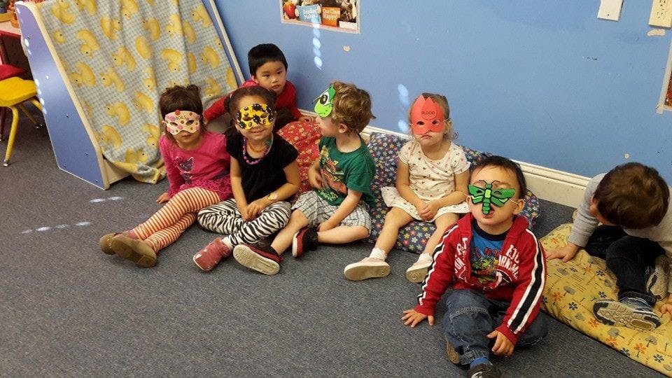 Children wearing masks sitting on the floor