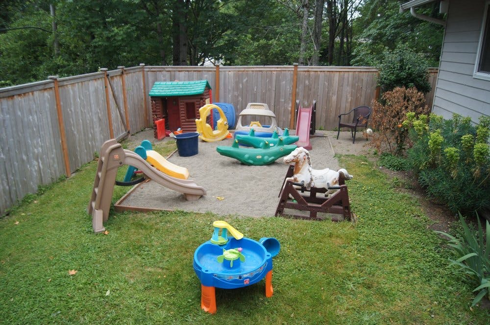 Sandbox with various playground toys, including slides, a playhouse, and rocking animals