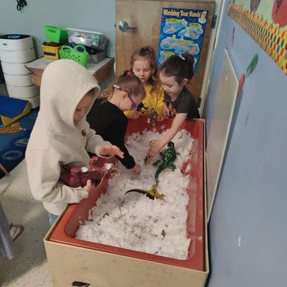 Children playing with toys in a sensory bin filled with white material