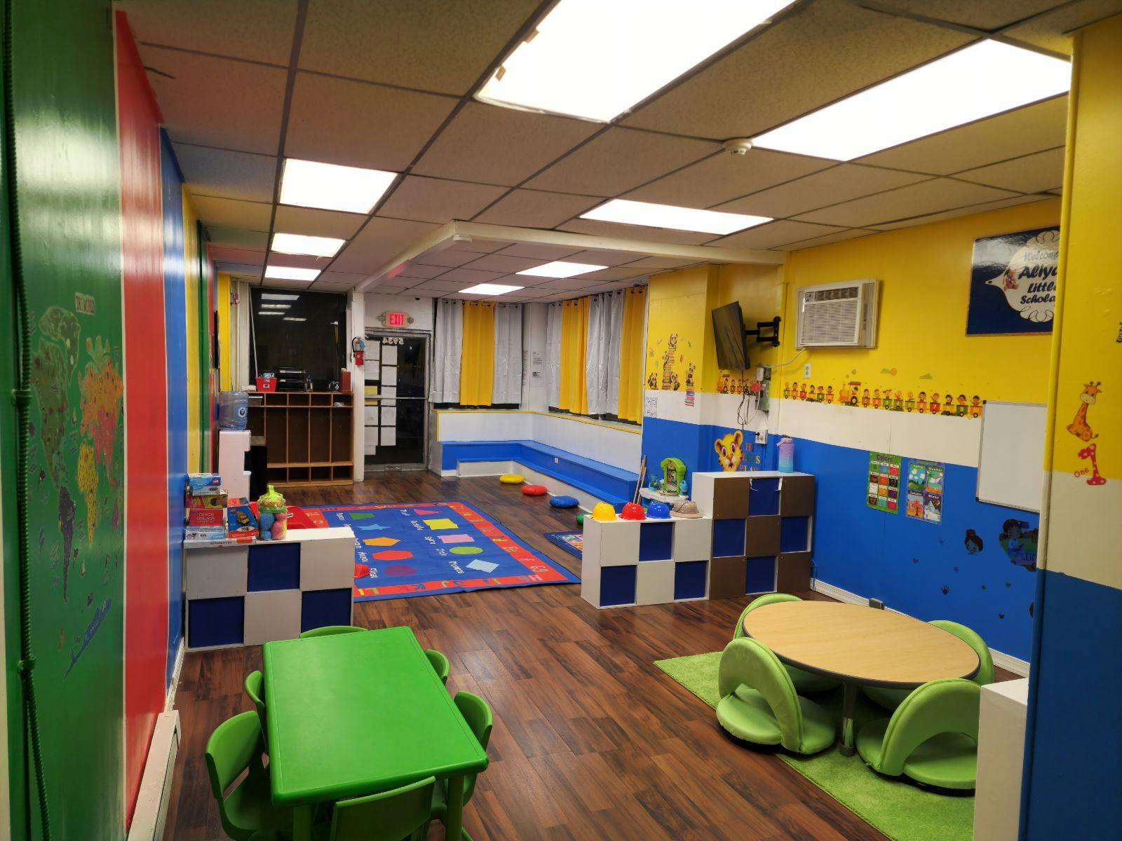 Playroom with colorful walls, small tables, and a rug with blue and white checkered blocks