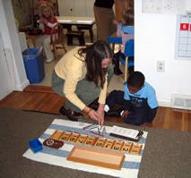 Adult and child on floor with learning materials