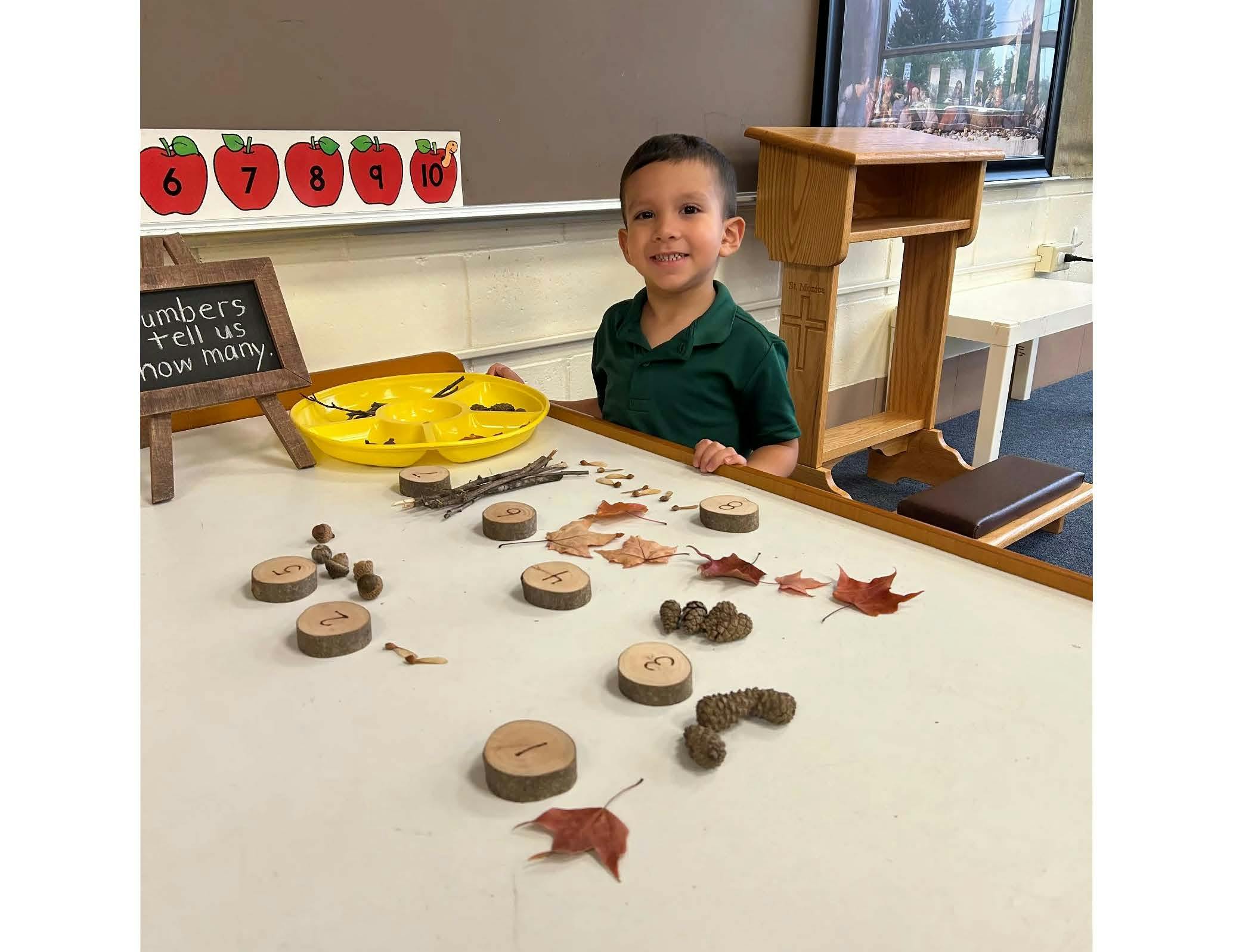 Child standing behind a table with natural elements and wooden counting materials