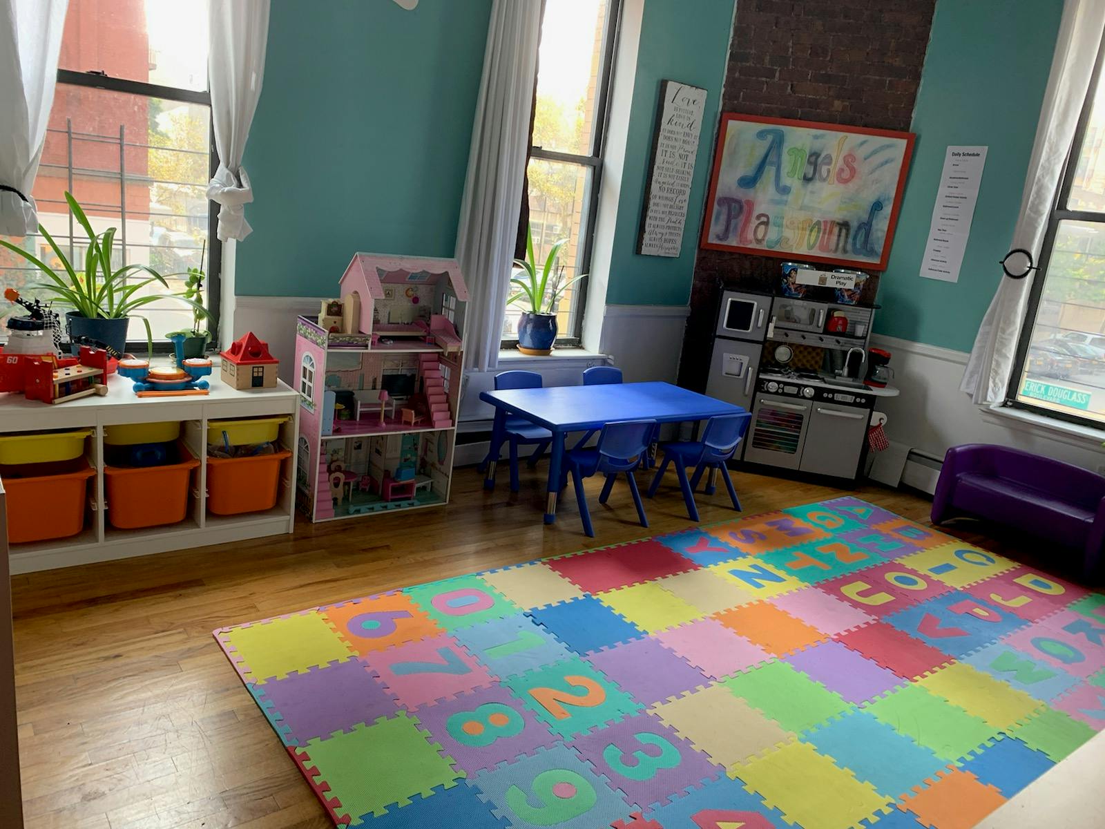 Playroom with colorful alphabet mat, blue table and chairs, and toy kitchen