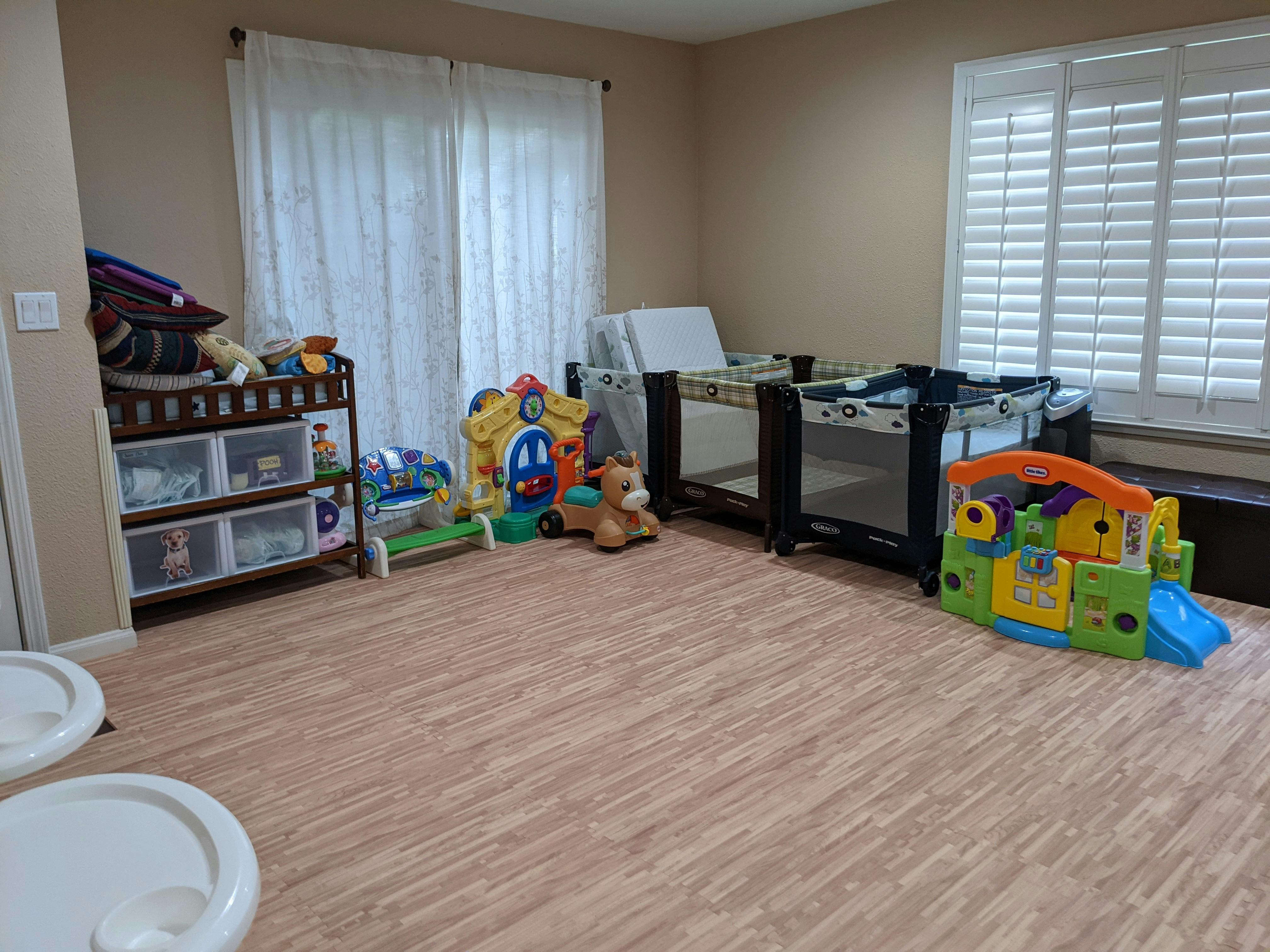 Room with two cribs, a changing table, and children's toys