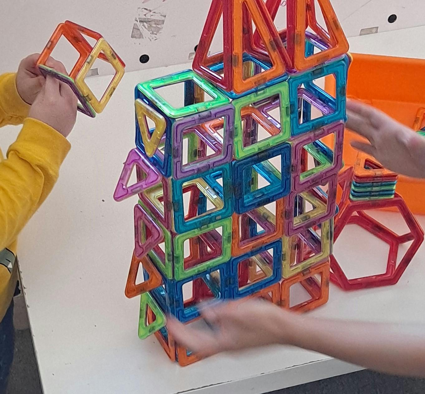 People building a tower with colorful magnetic tiles
