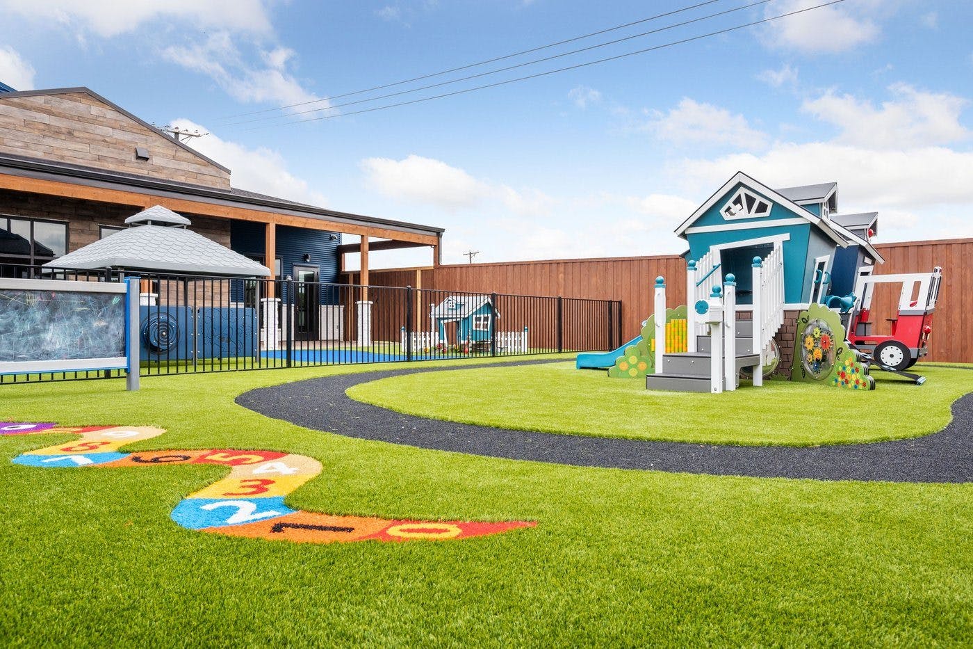 Outdoor playground with artificial turf, play house, and numbered markings