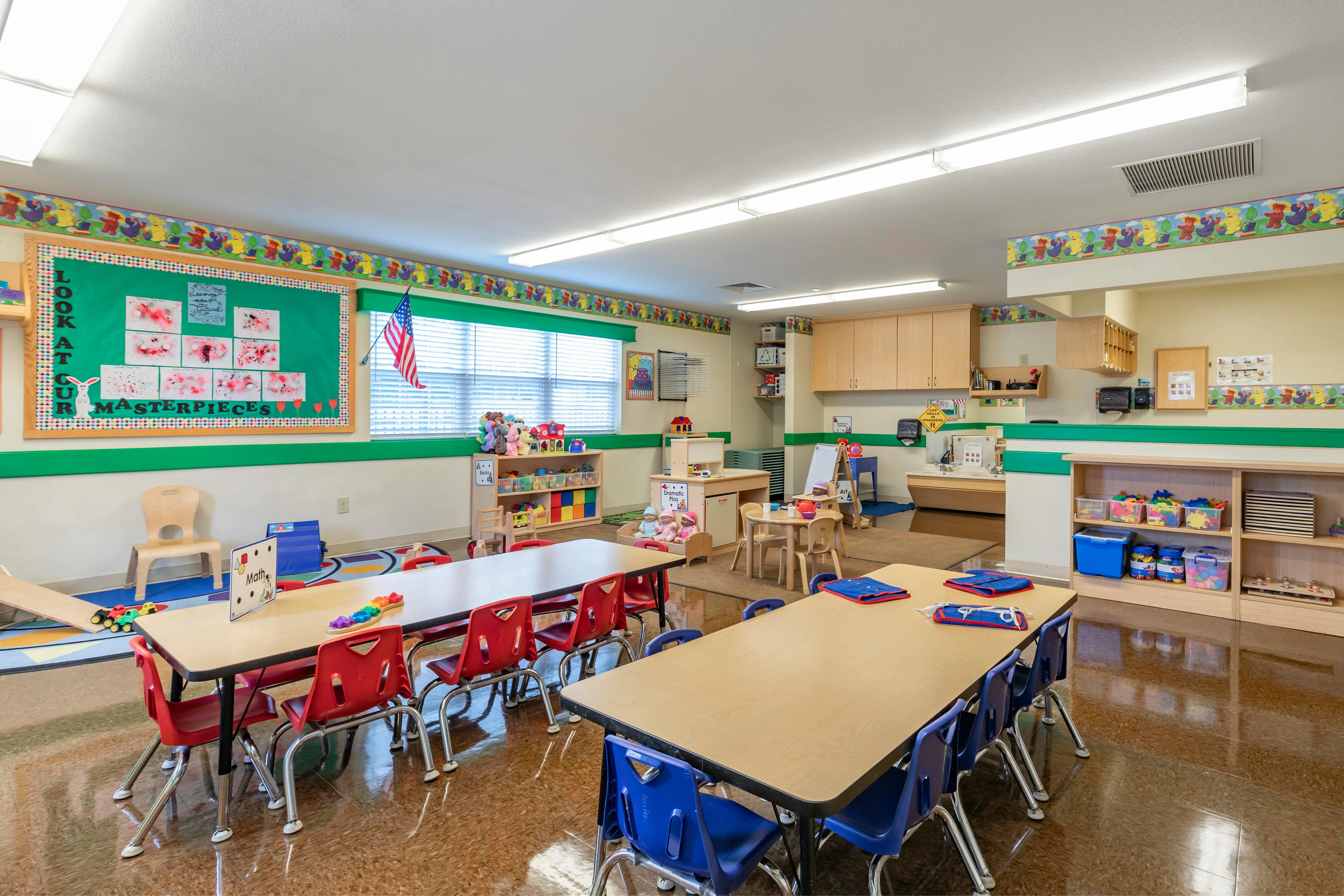 empty preschool classroom with small tables and chairs