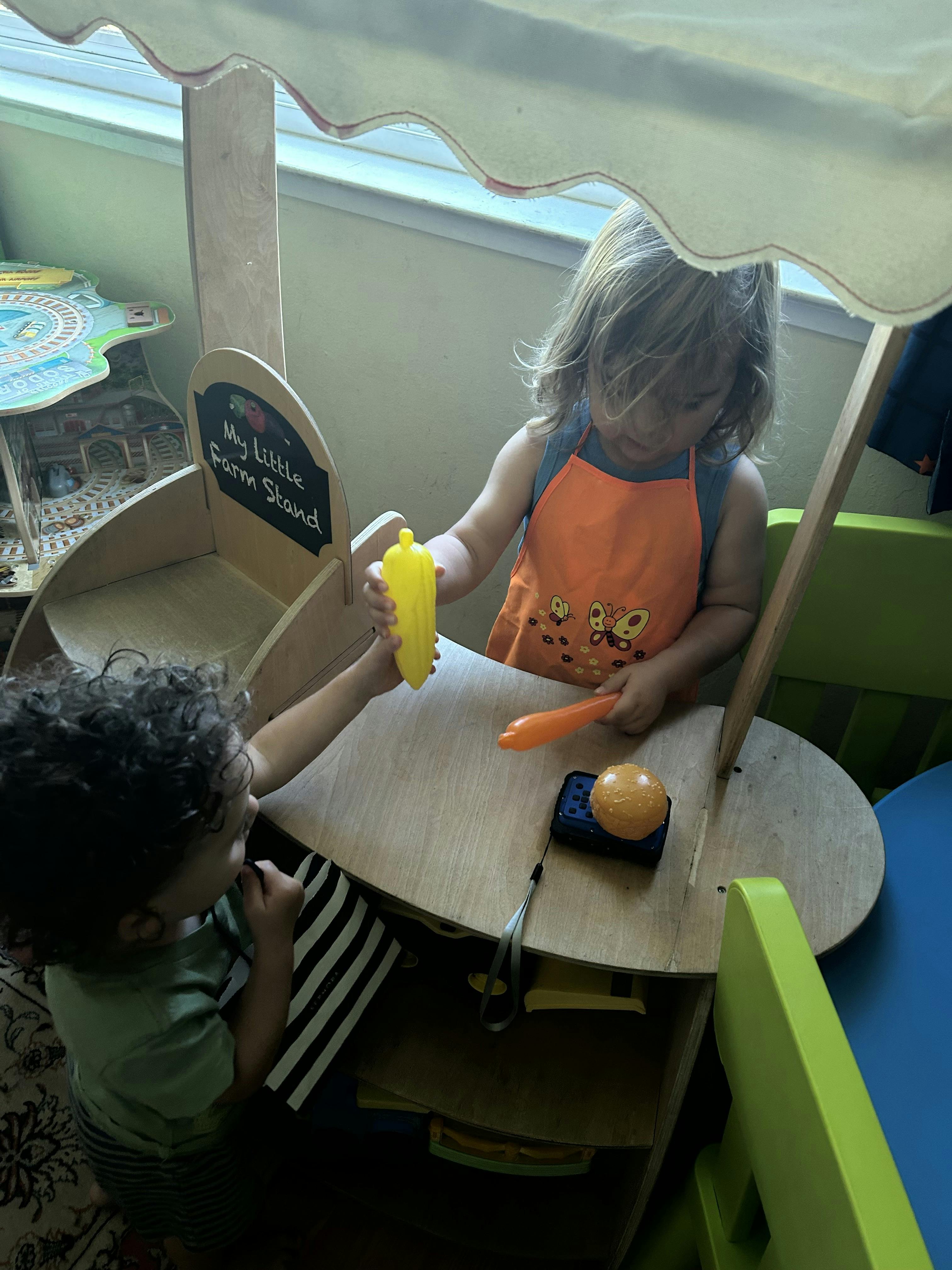 Two children playing with toy food at a play stand