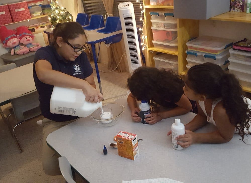 Person pouring liquid into a bowl with two children watching