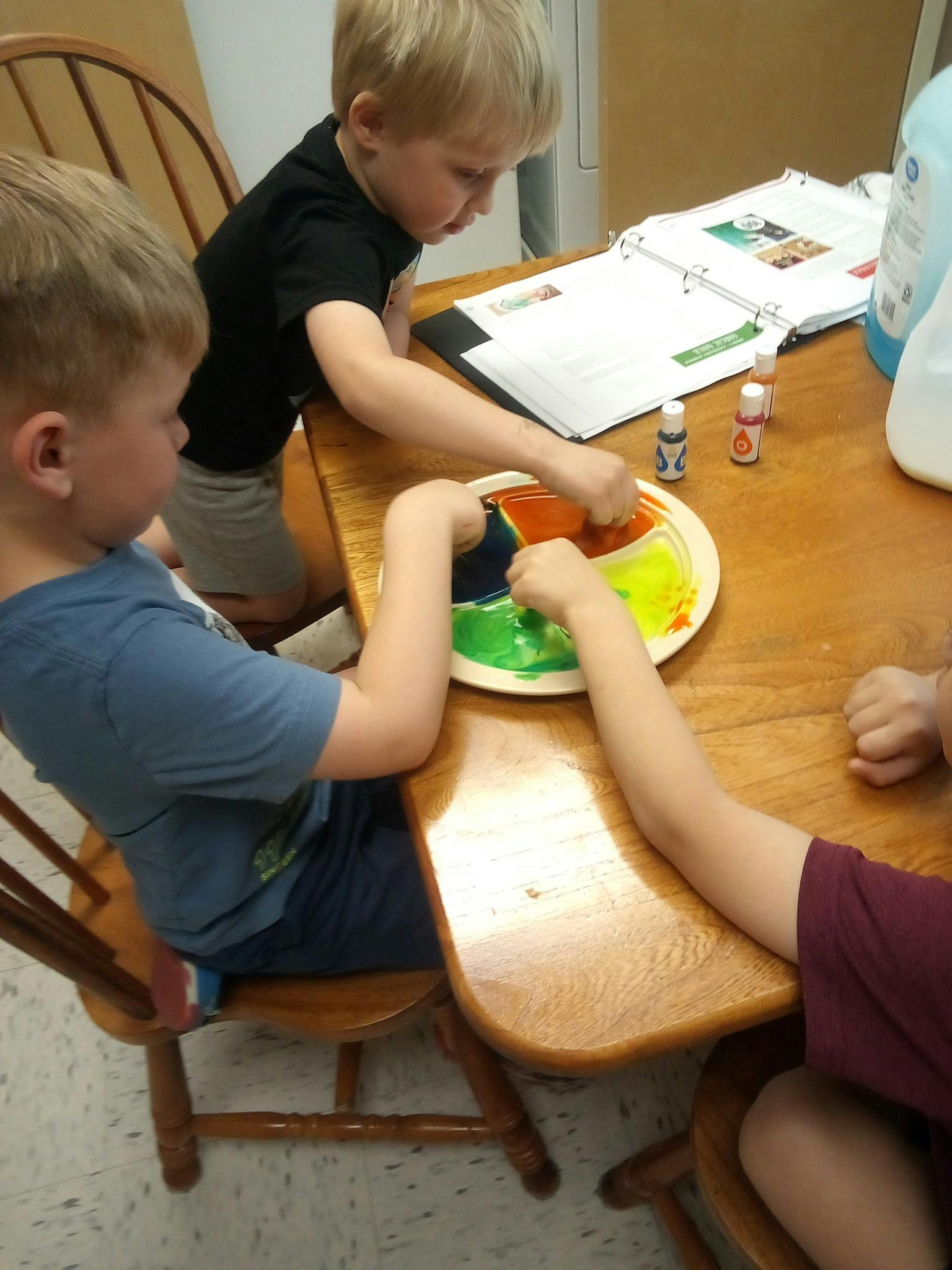 Children at a table with a divided plate of colorful liquids