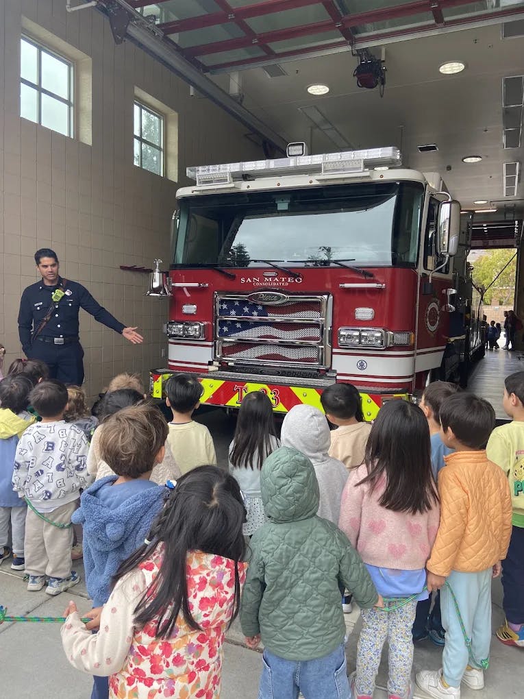 Firefighter talking to a group of children in front of a fire truck