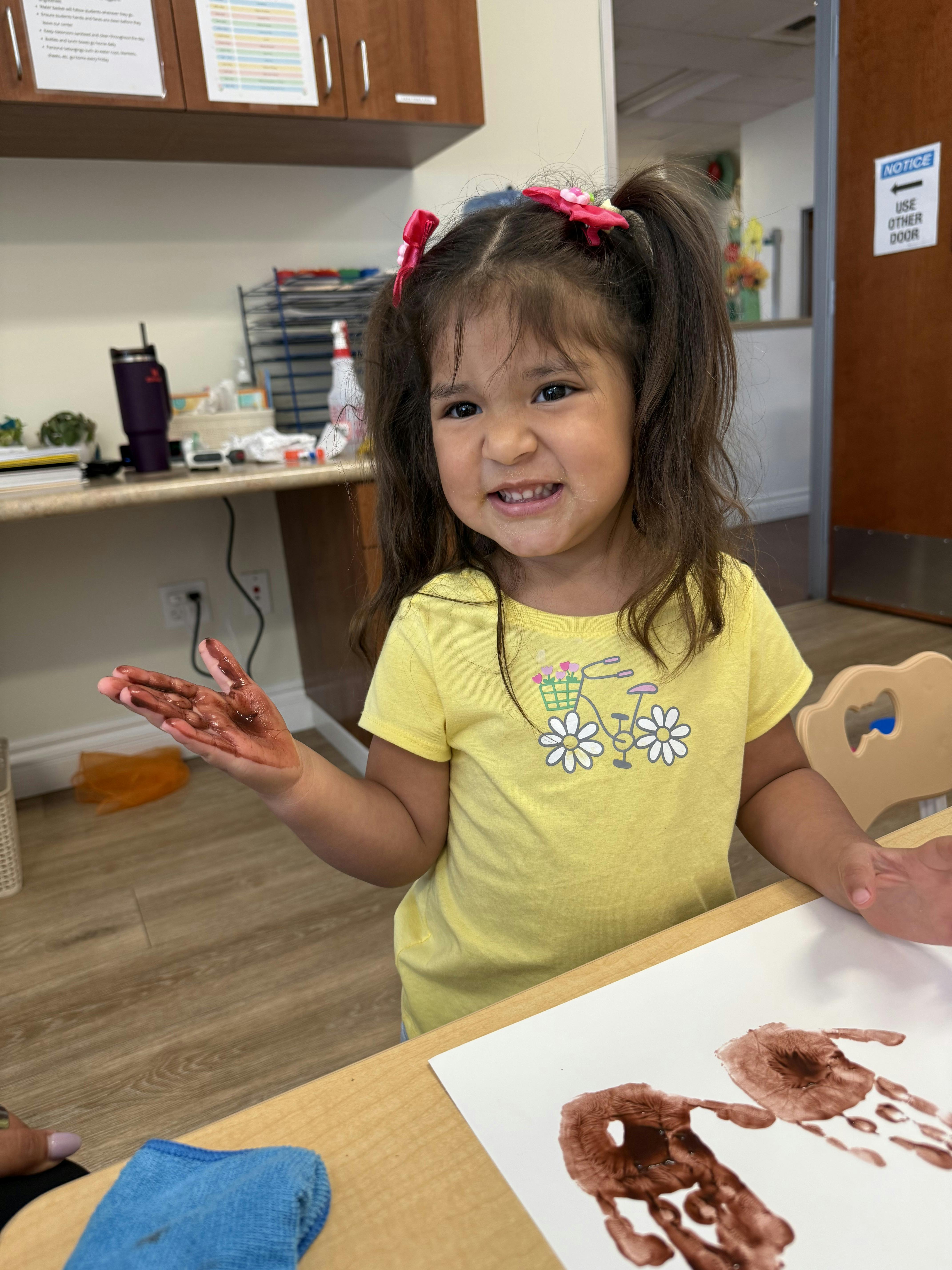 Child with paint on hands and paper making handprints