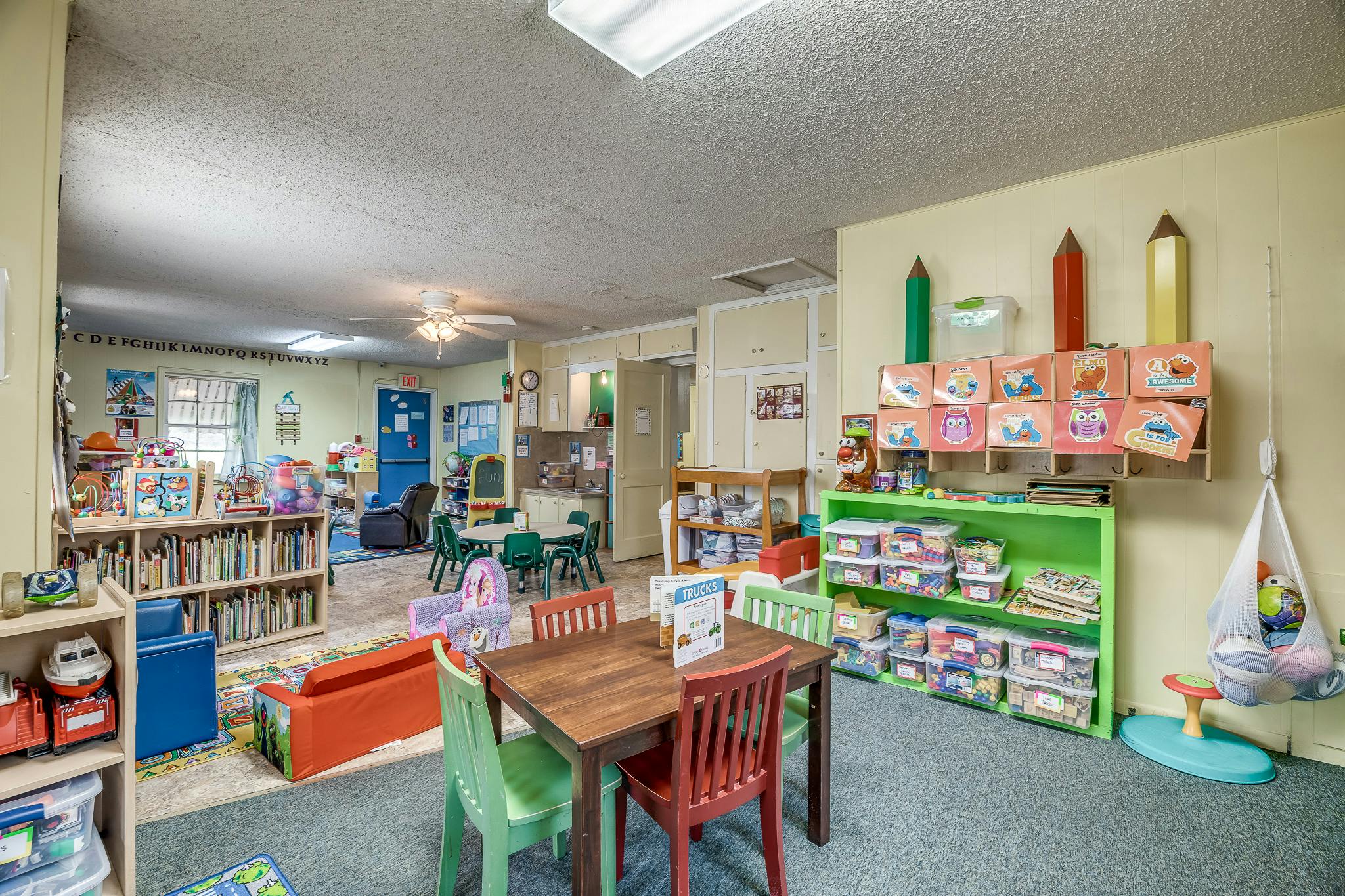 A classroom with tables, chairs, bookshelves, and storage for toys and art supplies