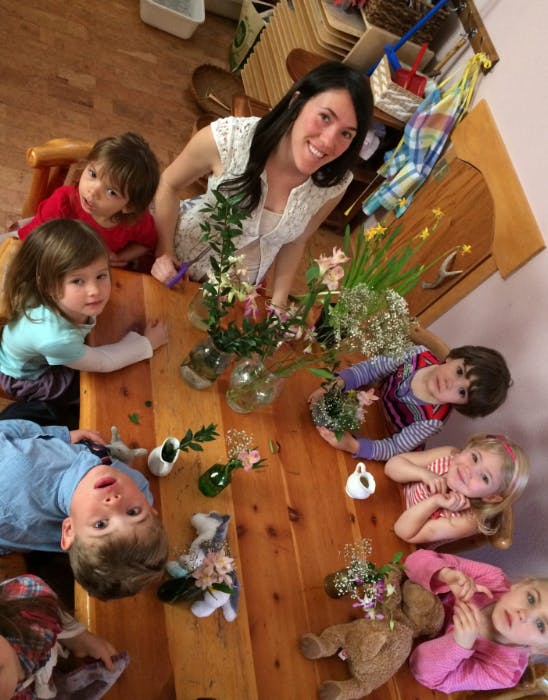 Person and multiple children around a table with flowers