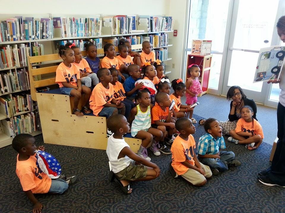 Children listening to a person read a book in a library