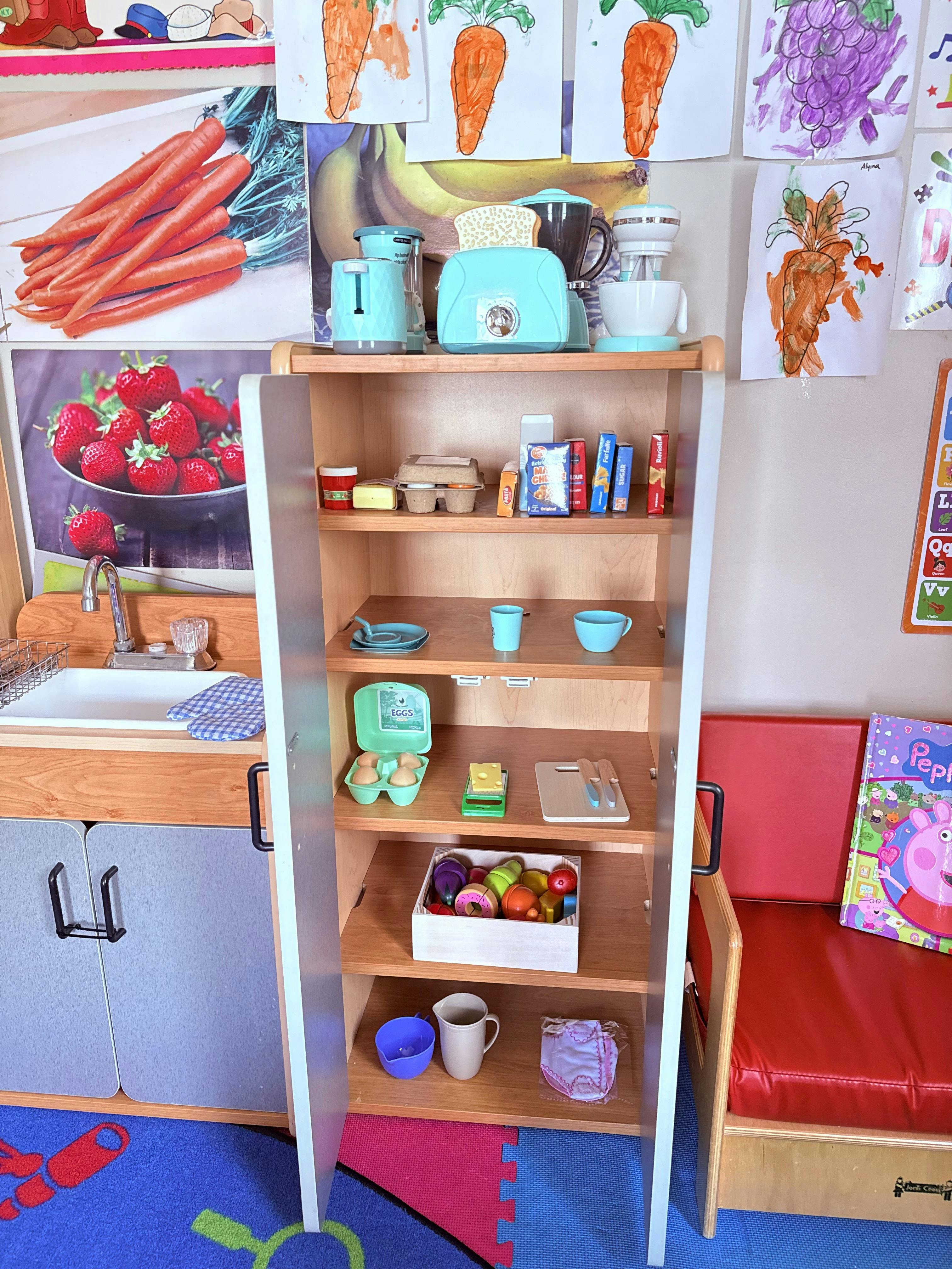 Toy kitchen cabinet with play food and kitchenware