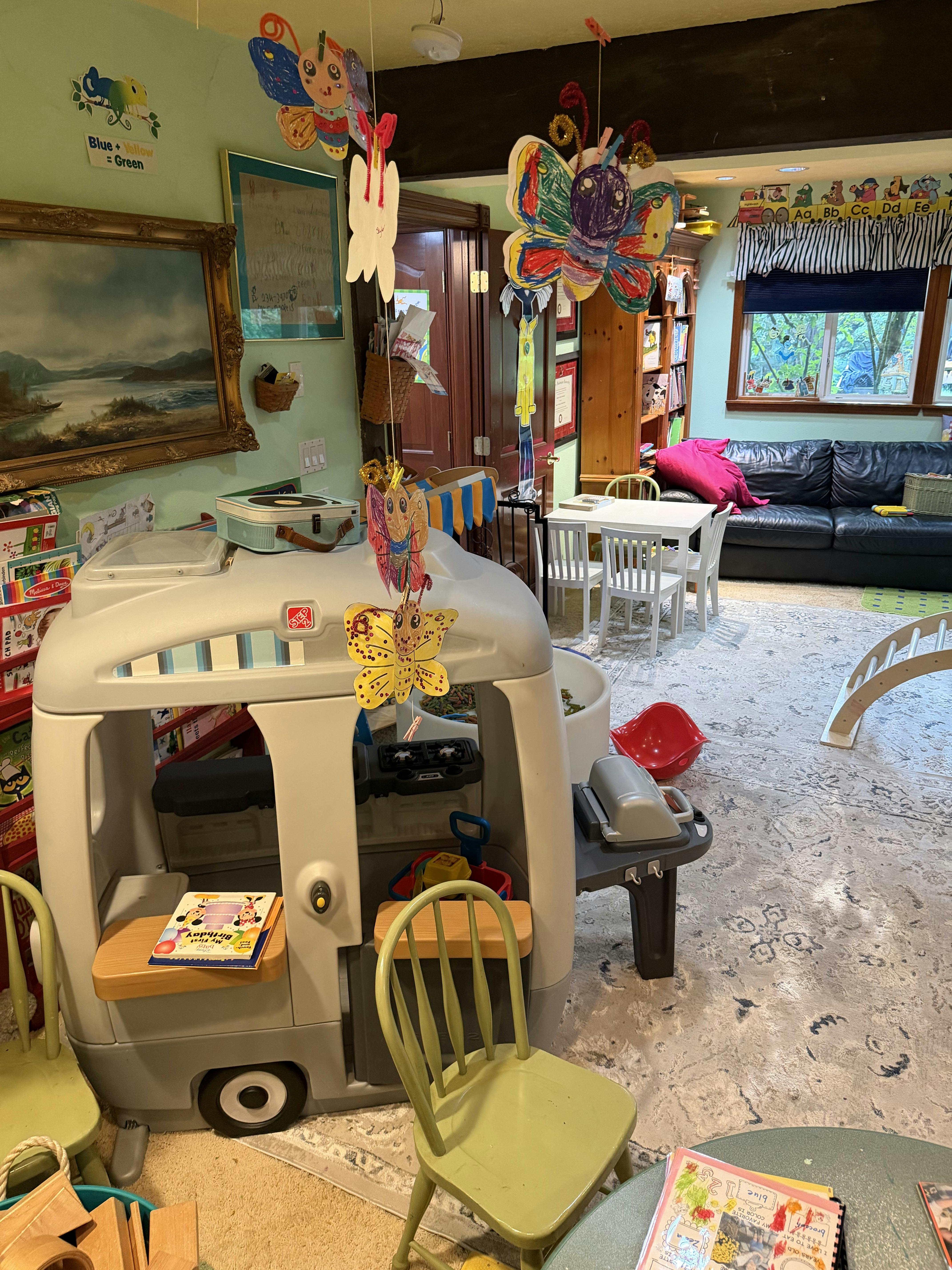 Playroom with plastic playhouse, children furniture, and hanging butterfly crafts