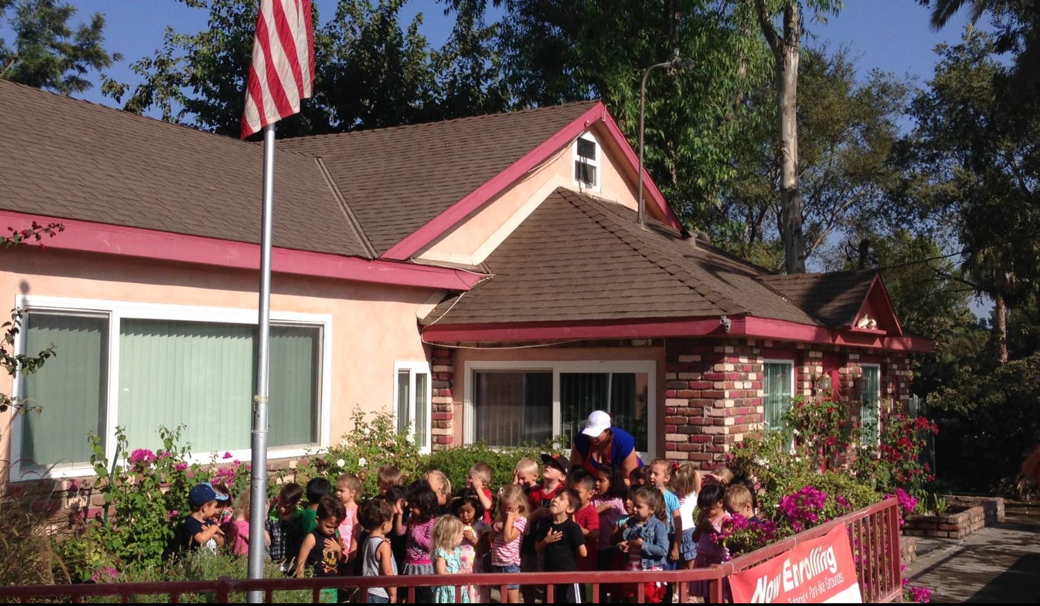 Group of children and adults in front of a building with an American flag