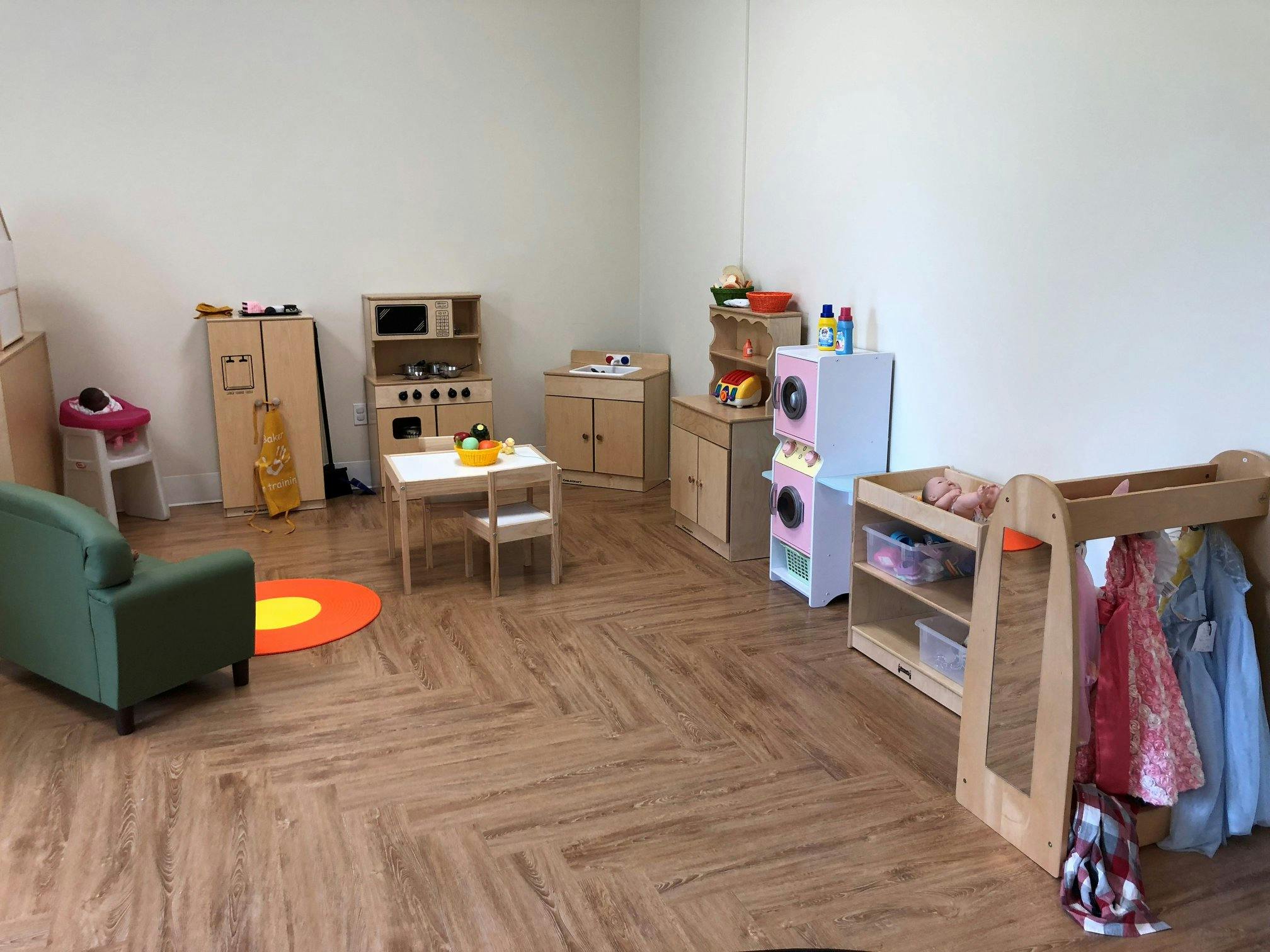 Playroom with toy kitchen, table and chairs, and clothing rack