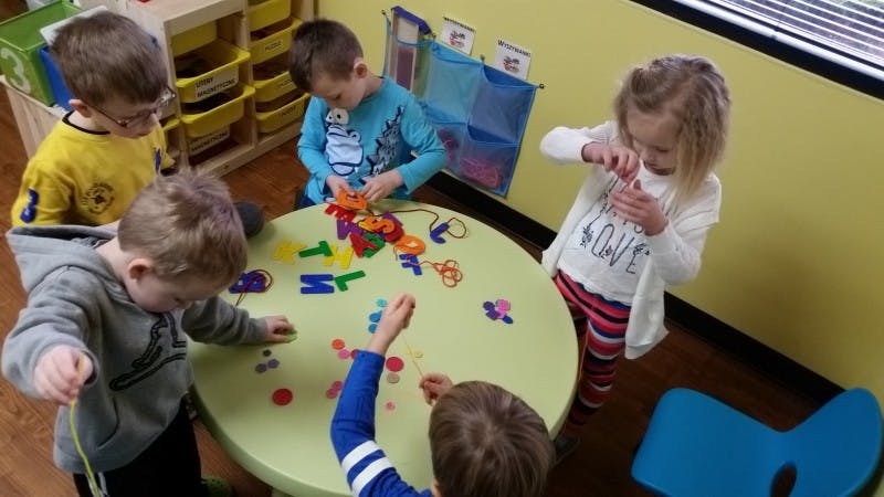Children playing with colorful letters and shapes at a table