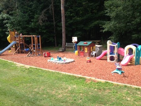 Outdoor playground with slides, swings, and playhouses on wood chips