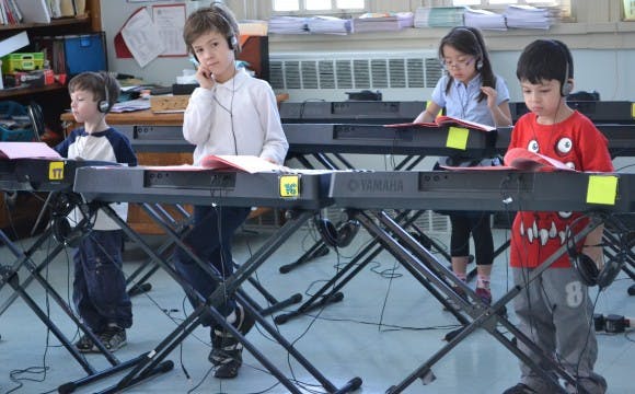 Children wearing headphones at keyboards in a classroom