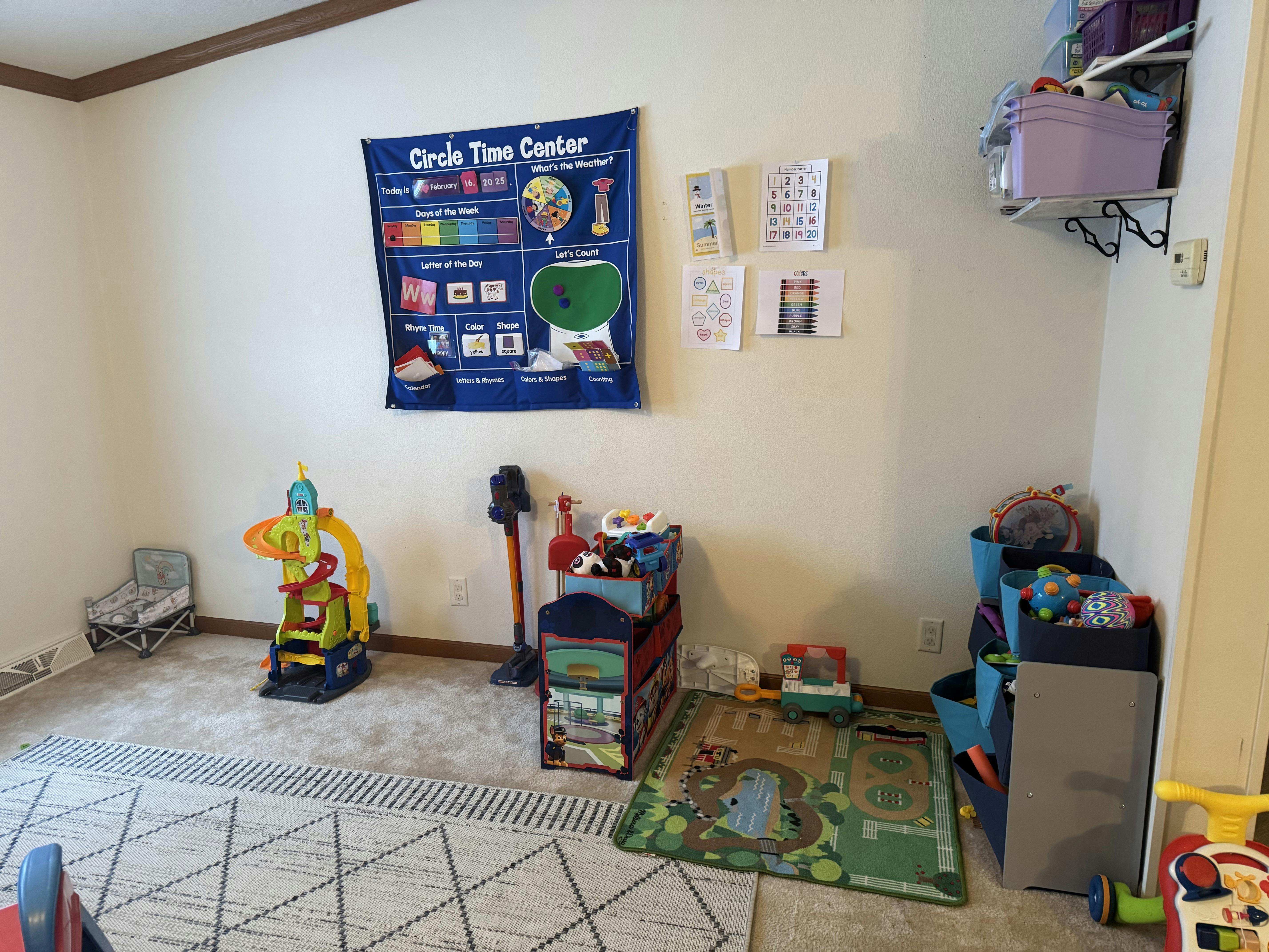 A playroom with various toys, a rug, and a "Circle Time Center" learning chart on the wall