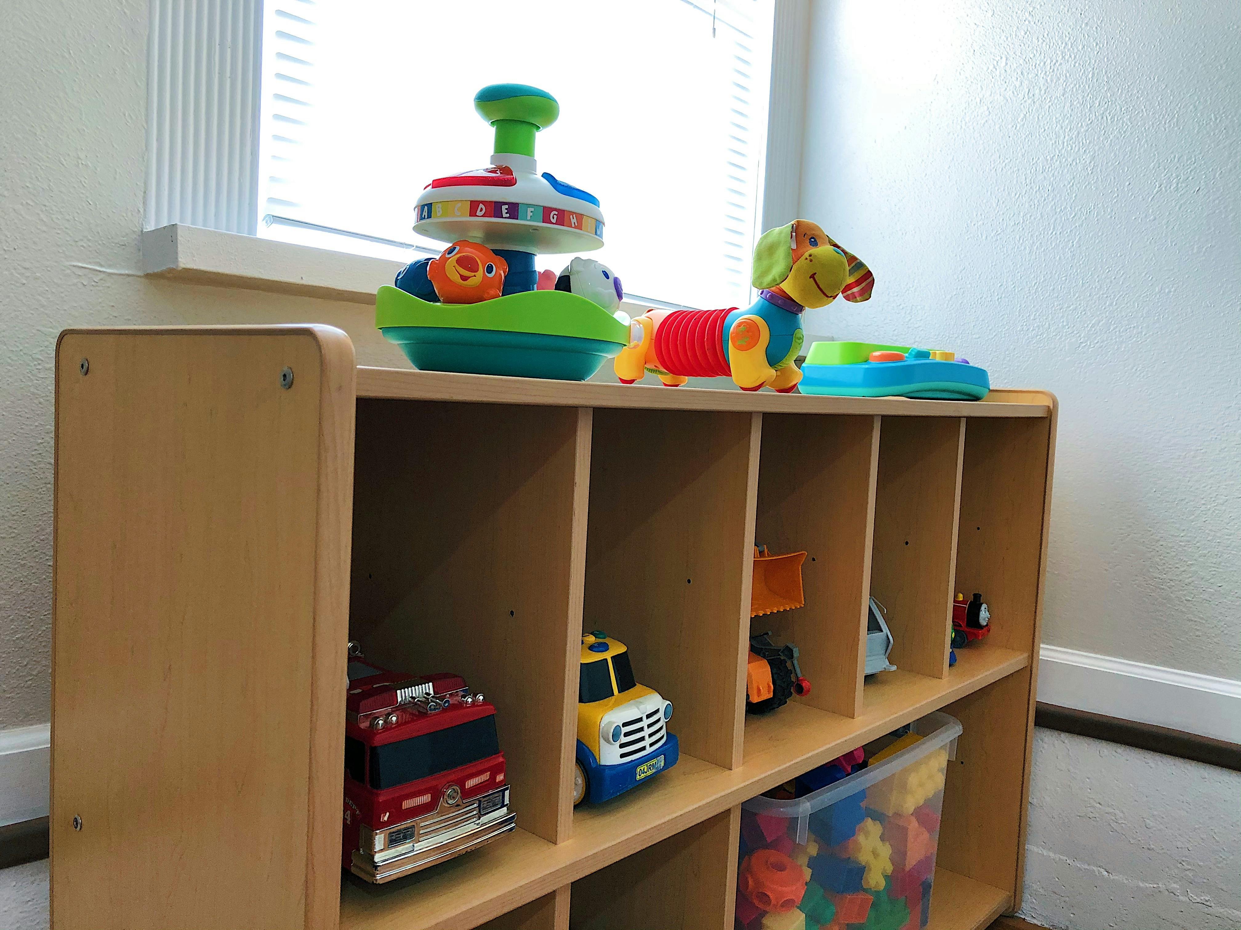 Wooden toy shelf with various toys including trucks and a dog toy