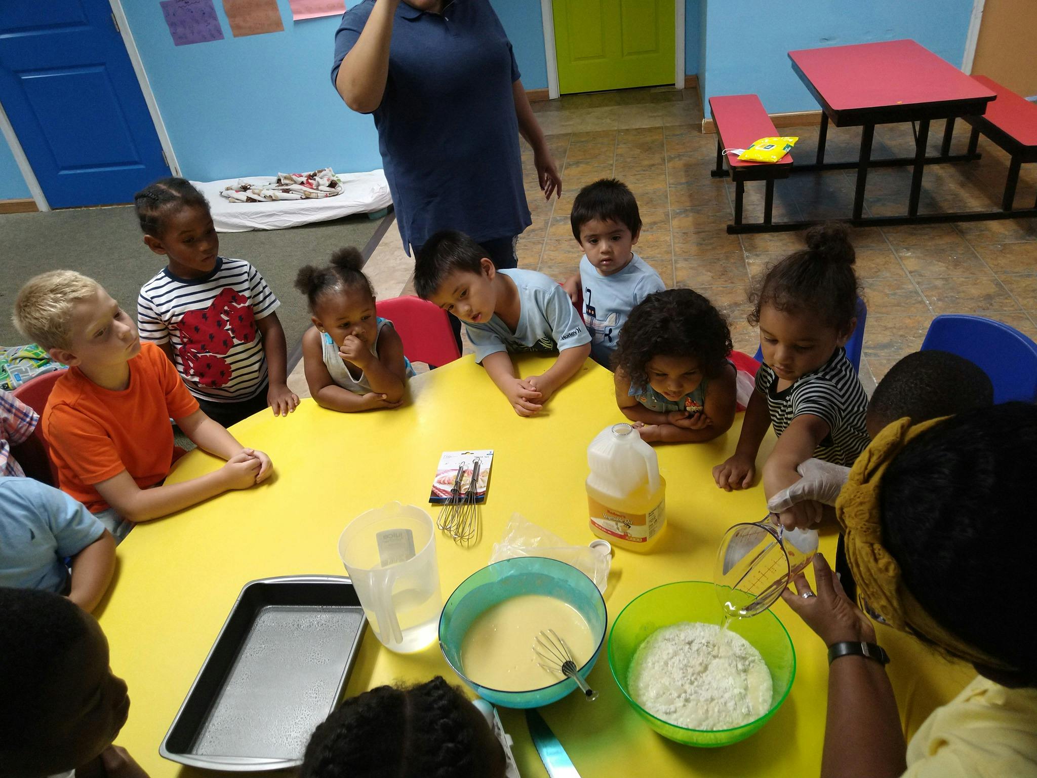 Children and adults gathered around a table with baking ingredients