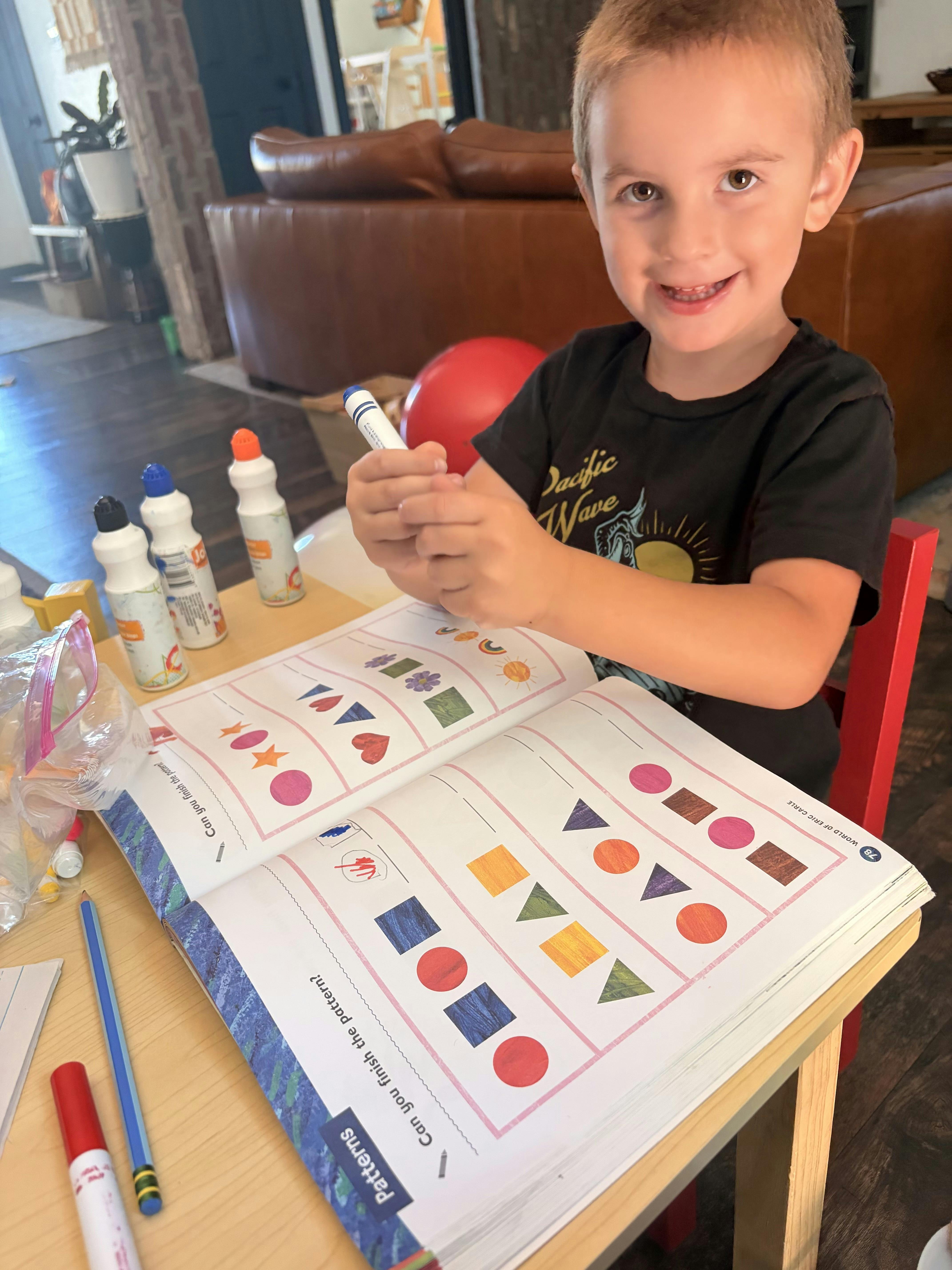 Child completing a shape pattern activity in a workbook