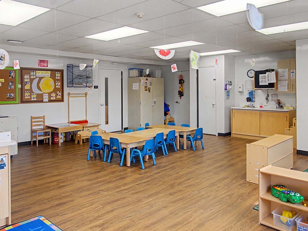 empty preschool classroom with small tables and chairs