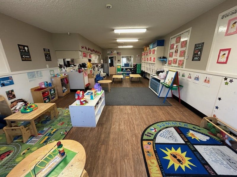 Children's classroom with small tables, chairs, toys, and educational posters