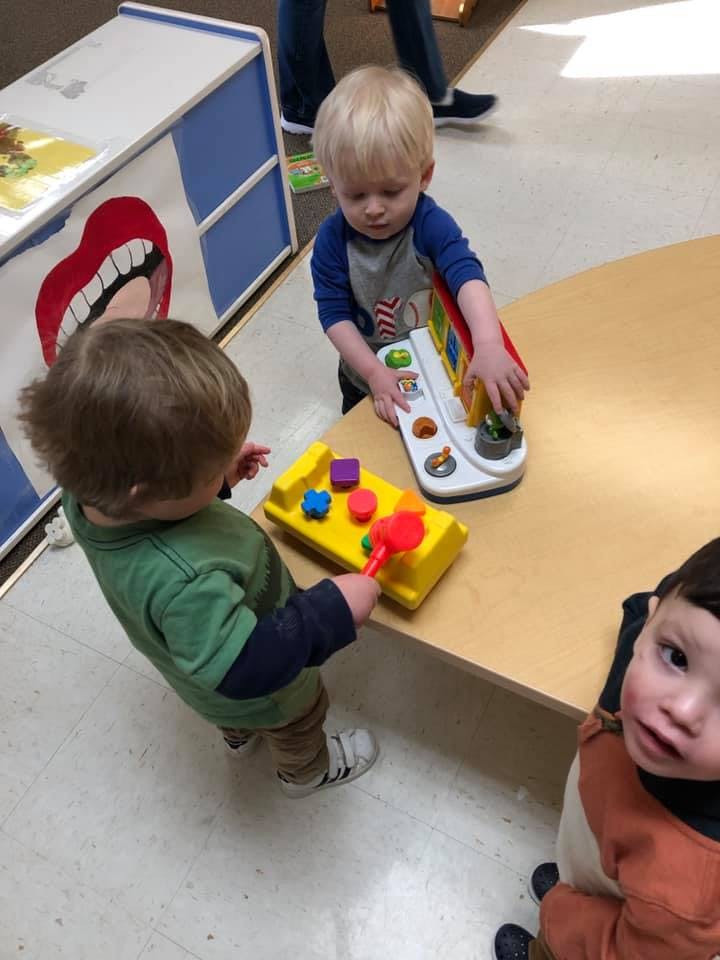 Three children playing with toys on a table