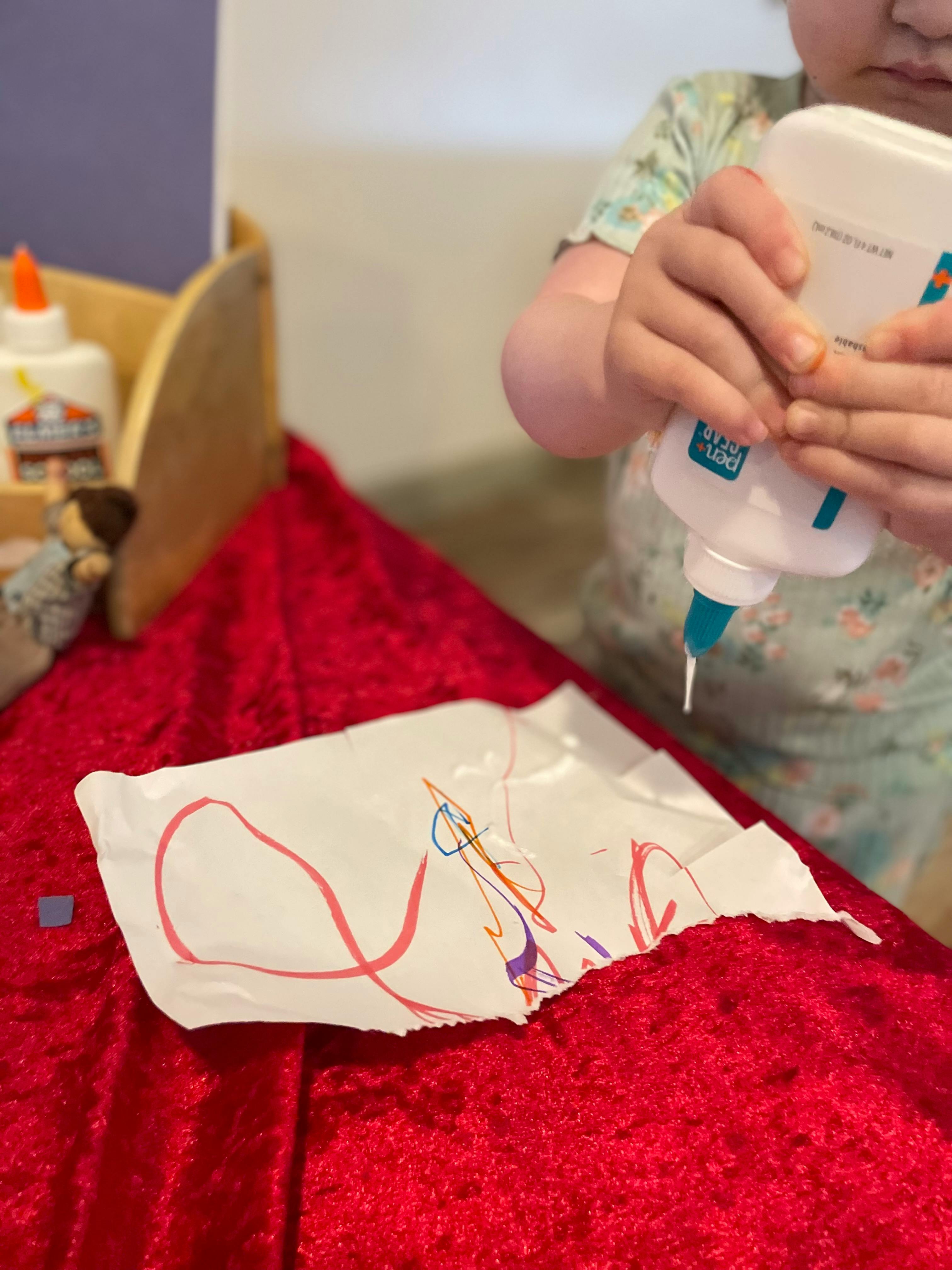 Child squeezing glue onto a piece of paper
