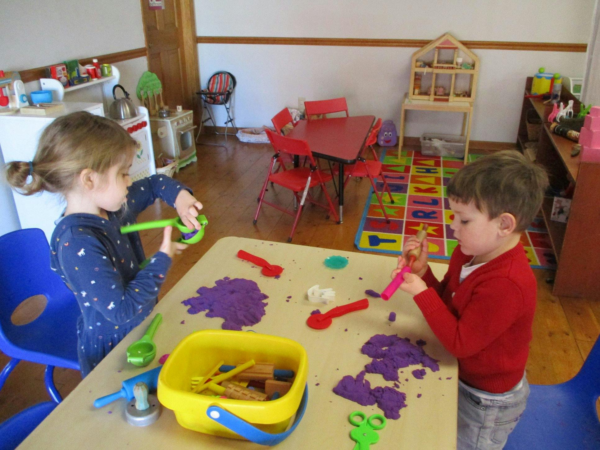 Two children playing with kinetic sand at a table