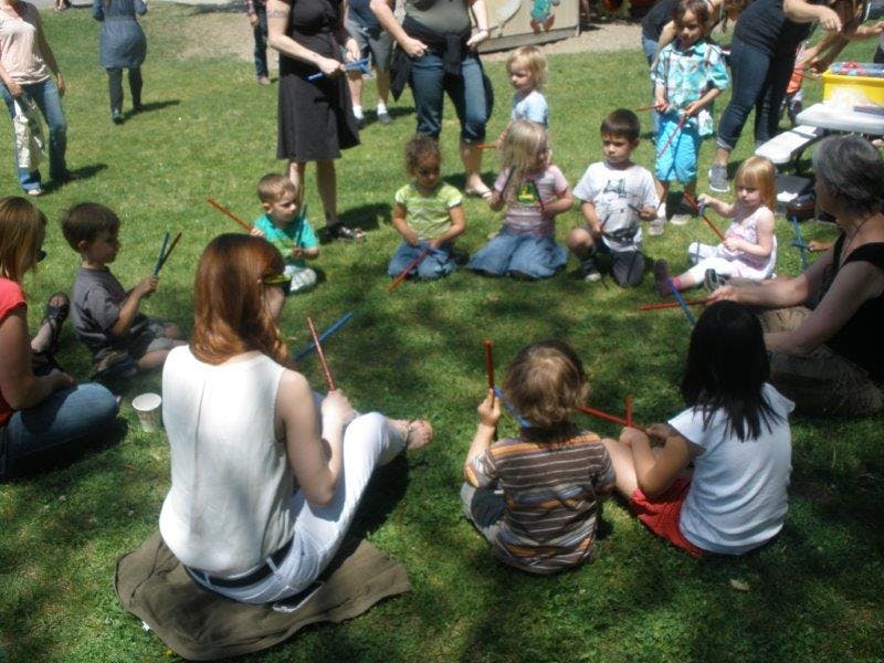 Adults and children sitting in a circle on grass