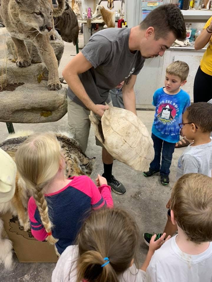 Person holding a large turtle shell for children to see
